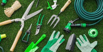 Gartenwerkzeuge auf grünem rasenteppich pflanzschaufel Gartenschere, gartenhandschuhe, wasserschlauch